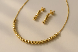 نیم‌ست طلا زنانه کلاسیک شامل گردنبند و گوشواره طلایی ساده با طراحی مهره‌ای و هماهنگ، مناسب برای انتخاب هوشمندانه 